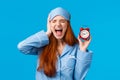 Upset and distressed screaming redhead lovely girl feeling bothered and depressed, holding red alarm clock and shouting Royalty Free Stock Photo