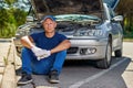 Upset driver man in front of old automobile broken car in city road