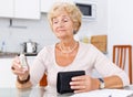 Upset elderly woman sitting at kitchen