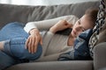 Upset female lying on couch with smartphone in hands