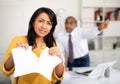 Upset female office employee tearing piece of paper