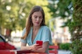 Upset female sitting in cafe, checking phone, biting lips