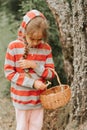 Upset or focused eight year old kid girl mushroom picker is seek for and picking mushrooms in the forest or woodland. child surviv Royalty Free Stock Photo