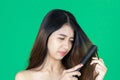 Upset frustrated young Asian woman holding damaged dry hair on hands over green isolated background Royalty Free Stock Photo