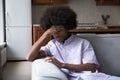 Upset fuzzy haired Black teen guy sitting on couch Royalty Free Stock Photo