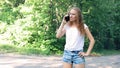 Upset girl expressively talking on the mobile phone against the background of trees in the park