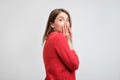 Upset girl in red sweater holding her hands on her chin being scared after what she did. Royalty Free Stock Photo