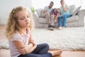 Upset girl sitting on floor while parents enjoying with brother Royalty Free Stock Photo