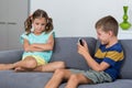 Upset girl sitting on sofa while boy using mobile phone in living room Royalty Free Stock Photo