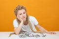 Upset girl sitting at table, propped her head on her hand, crumpled money lie in front of her on table Royalty Free Stock Photo