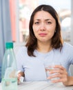 Upset girl suffering from troubles at table with bottled water Royalty Free Stock Photo