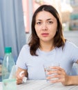 Upset girl suffering from troubles at table with bottled water Royalty Free Stock Photo