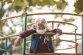 Upset girl wearing a mask on the playground, protecting against a pandemic. Boredom during quarantine, social distance