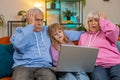 Upset grandfather grandmother and granddaughter playing game on laptop and losing fail at home sofa Royalty Free Stock Photo