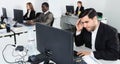 Upset Hispanic businessman worriedly looking at computer monitor in modern open plan office Royalty Free Stock Photo