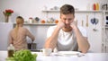 Upset hungry man waiting for dinner, wife cooking on background, divorce risk