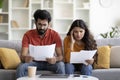 Upset indian couple checking bills, sitting on couch, reading documents Royalty Free Stock Photo