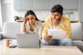 Upset indian couple checking papers and using laptop at home Royalty Free Stock Photo