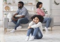 Upset little black girl sitting separately from parents after their argue Royalty Free Stock Photo