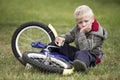 Upset little boy sits near to his bike