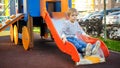 Upset little boy sitting on the slide at children playground Royalty Free Stock Photo