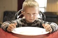 A Upset little boy waiting for dinner while holding a fork and a spoon Royalty Free Stock Photo