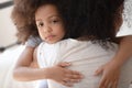 Upset little cute mixed race girl hugging mom.