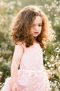 Upset little girl with curls walks in chamomile field Royalty Free Stock Photo