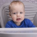 Upset little kid in a baby chair looking at camera Royalty Free Stock Photo