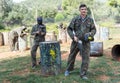 Upset loser paintball player in camouflage with mask leaving battlefield