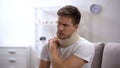 Upset man in foam cervical collar suffering pain in back and shoulder, injury Royalty Free Stock Photo