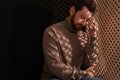 Upset man listening to priest during confession in booth, space for text Royalty Free Stock Photo