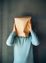 Upset man with a paper bag on head touching temples, suffering from strong tension headache Royalty Free Stock Photo