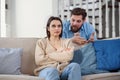 Upset man at table and woman with shopping bags in room. Money problems in relationship Royalty Free Stock Photo