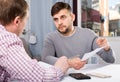 Man with friend looking worriedly at papers at home table Royalty Free Stock Photo