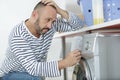 Upset man sitting next to washing machine Royalty Free Stock Photo