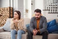 Upset man at table and woman with shopping bags in room. Money problems in relationship Royalty Free Stock Photo