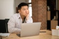 Upset mature asian man feeling bored, sitting with laptop at table during online business meeting at home, copy space Royalty Free Stock Photo