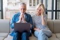 Upset mature couple looking at computer and getting shocking bad news Royalty Free Stock Photo