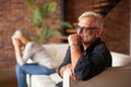 Upset mature husband is sitting on the couch with his wife. Divorce of an older couple, crisis in family relations Royalty Free Stock Photo