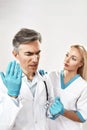 Upset mature male doctor feeling depressed, his female colleague comforting him while standing against grey background Royalty Free Stock Photo