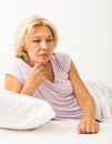 Upset mature woman laying in bed