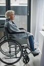 Upset mature woman sitting in wheelchair in room