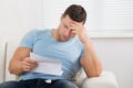 Upset Man Reading Letter On Sofa At Home Royalty Free Stock Photo