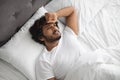 Upset middle eastern guy laying alone in bed
