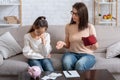 Upset mother and her daughter with empty wallet and heap of unpaid bills having financial problems at home