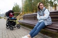 upset mother sits on a bench separated from the pram with her baby, the concept of postpartum depression Royalty Free Stock Photo