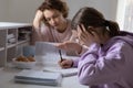 Upset mother and teenage daughter studying at home