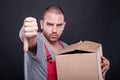 Upset mover man holding box showing thumb down Royalty Free Stock Photo