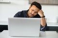 Upset multi-ethnic man is using laptop sitting at home alone Royalty Free Stock Photo